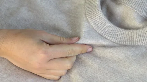 Hand smoothing sweater surface showing fabric softness and quality. Useful for Video stock 332875907