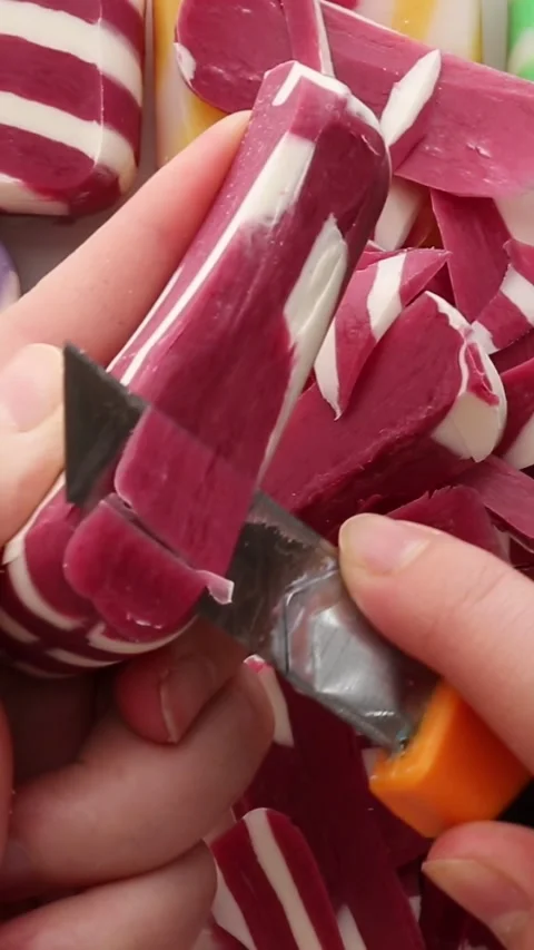 A hand smoothly cutting a red-striped soap bar, showcasing soft textures and Stock Footage 313753414