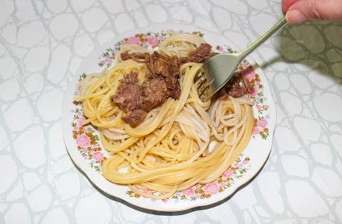 Hand snagging a fork from a plate of spaghetti. Foto stock