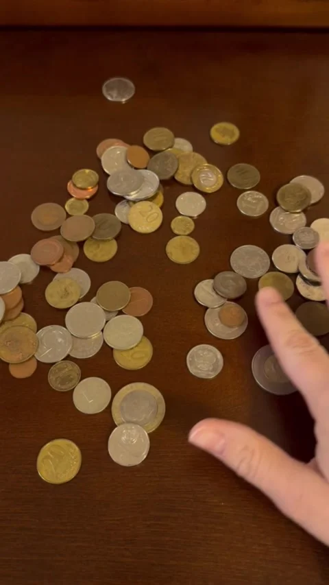 Hand sorting and selecting scattered coins on dark wooden table closeup view Stock Footage 321749613