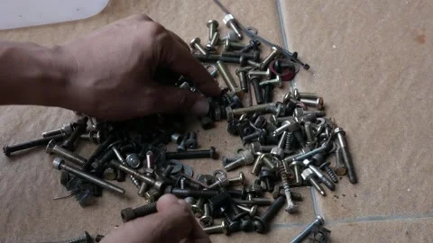 Hand Sorting Mixed Screws, Bolts and Nuts on Floor Stock Footage 336804426
