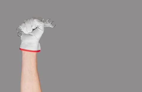Hand with spanner in white glove. Work background with house and wall equip.. Foto stock