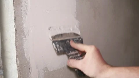 Hand with a spatula to apply putty on the wall. Master's hands apply the Stock Footage 267097839