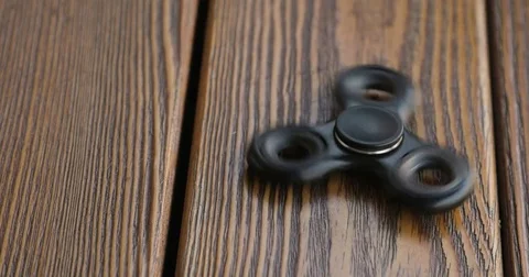 Hand spinner, or fidgeting spinner, rotating on the floor. wooden background. Stock Footage 76631046