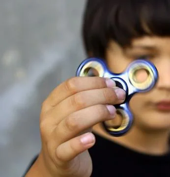 Hand spinner or fidgeting spinner rotating on child's hand Stock Photos