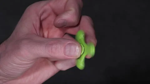 Hand spins green fidget spinner, showcasing continuous motion and grip Vídeos de archivo 344749567