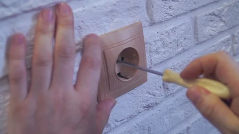 The hand spins the socket with a screwdriver and removes it the 库存影片 120287357