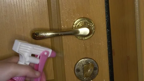 A hand splashes a spray on the surface of the door handle and wipes it Stock Footage 138973503