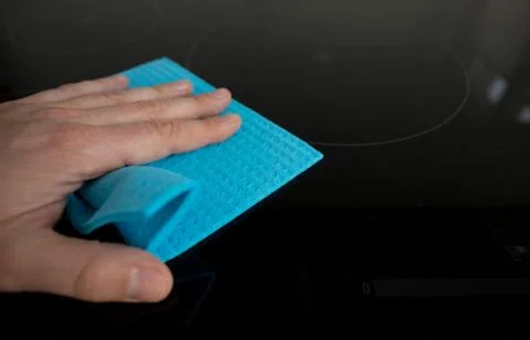 Hand with a sponge cleaning surface in kitchen Stock Photos
