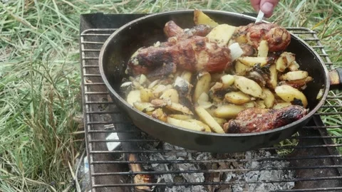 A hand with a spoon mixes potatoes with chicken drumsticks, fried in a fryin Vídeos de archivo 205872350