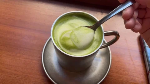 Hand with a spoon removing foam from matcha latte personal perspective Stock Footage 341429990