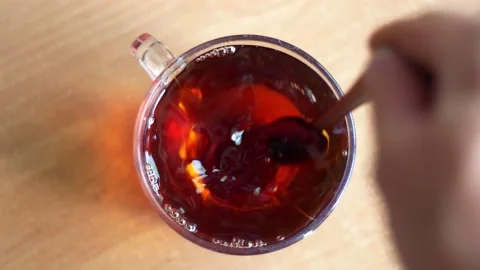 Hand spoon stirring sugar in a cup of tea on the table Stock Footage 144078728