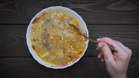 Hand with spoon stirs vegetable soup. Cooking process. Frame of soup from above. Stock Footage 105102899