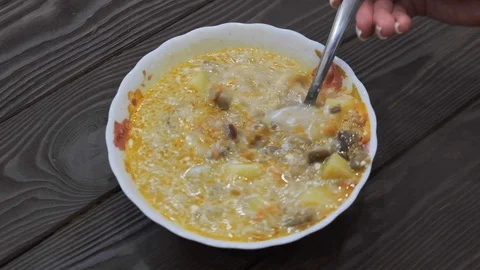 Hand with spoon stirs vegetable soup. Cooking process. Frame of soup from above. Stock Footage 105103024