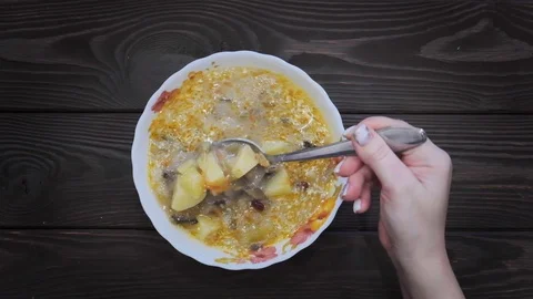 Hand with spoon stirs vegetable soup. Cooking process. Frame of soup from above. Stock Footage 105103030