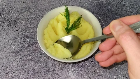 Hand with a spoon takes a portion of mashed potatoes for testing Stock Footage 230015425