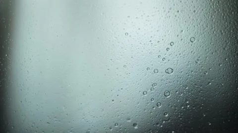 Hand spray liquid on glass to the camera. Drops flow down on glass. Cold tone Stock Footage 63160385