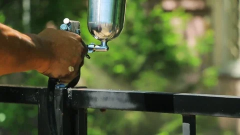 Hand spraying a black paint in slow motion on the fence in the park Stock Footage 76001430