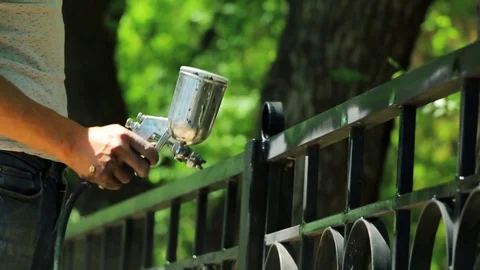 Hand spraying a black paint in slow motion on the fence in the park Stock Footage 76001450