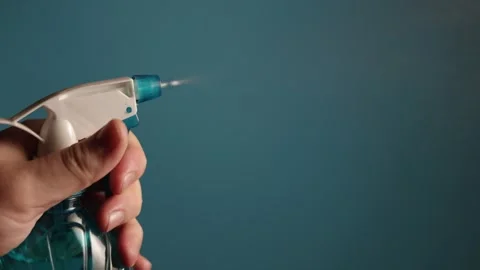 Hand spraying cleaning liquid from a blue bottle with a white trigger sprayer Stock Footage 340265804