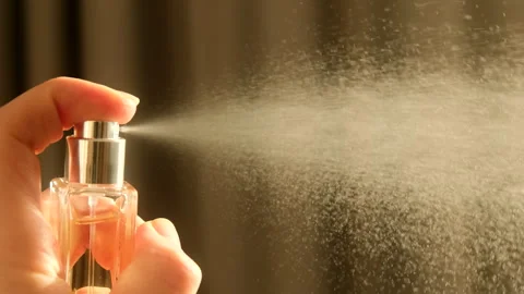 Hand spraying dust perfume bottle, releasing a fine mist into the air. Stock Footage 328983379