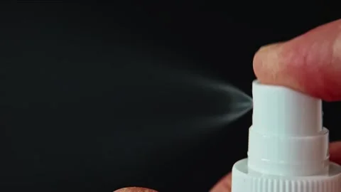 A hand sprays liquid from a white bottle in focus Stock Footage 332233799