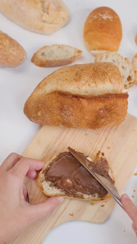 Hand Spreading Chocolate Hazelnut Cream on Sourdough Bread Slice Stock Footage 337519524