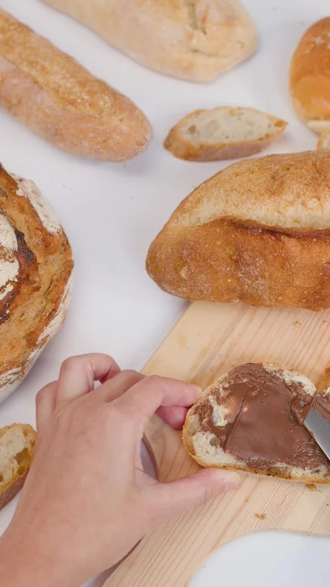 Hand Spreading Chocolate Hazelnut Cream on Fresh Sourdough Bread Slice Stock Footage 337520905