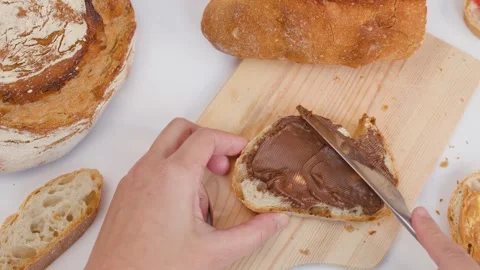 Hand Spreading Chocolate Hazelnut Cream on Sourdough Bread Slice Stock Footage 337917852