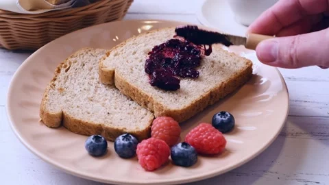 Hand spreading jam on a slice of bread with berries 스톡 동영상 302984967