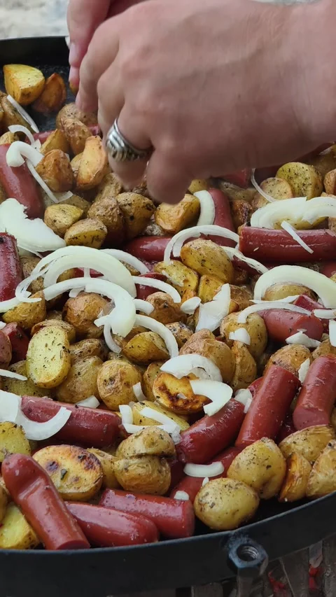 Hand Spreading Onions Over Potatoes and Sausages in a Pan Stock-Footage 314999546