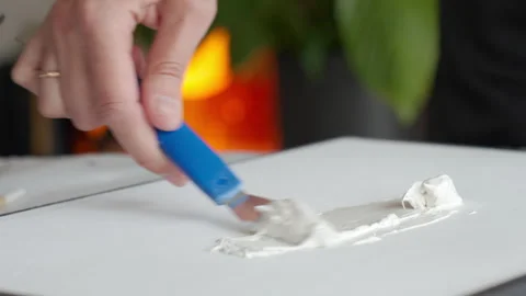 Hand spreading white texture paste on canvas with spatula Video stock 335131857