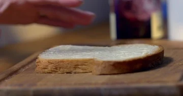 Hand spreads jam on slice of home-made buttered bread 4K 스톡 동영상 86138016