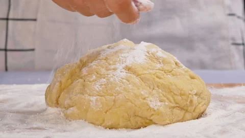 Hand sprinkle the flour onto the dough, preparing for the homemade donuts. Stock Footage 158092211