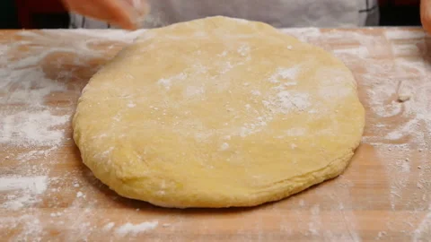 Hand sprinkle the flour onto the dough, preparing for the homemade pizza. Stockbeeldmateriaal 158092302