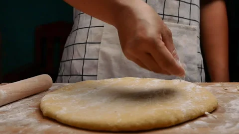 Hand sprinkle the flour onto the dough, preparing for the homemade pizza. Stock Footage 158092310