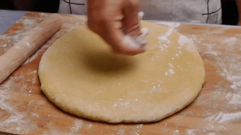 Hand sprinkle the flour onto the dough, preparing for the homemade pizza. Vídeos de archivo 158092314