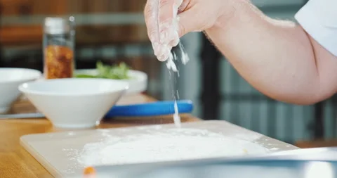 Hand sprinkling flour in kitchen, chef cooking dough in restaurant. Stock Footage 133240931