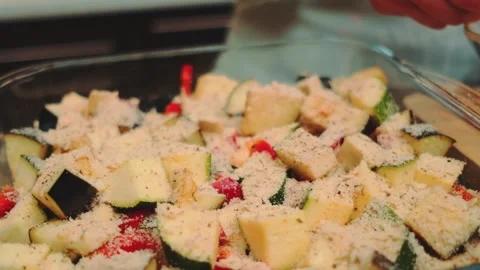 Hand Sprinkling Grated Cheese and Seasoning on Vegetables in Kitchen Stock Footage 342888534
