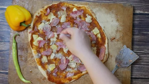 Hand sprinkling pepper on pizza with pineapple, pork , Bell pepper on wood Stock Footage 149576676