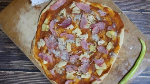 Hand sprinkling pepper on pizza with pineapple, pork , Bell pepper on  table Stock Footage 149576748