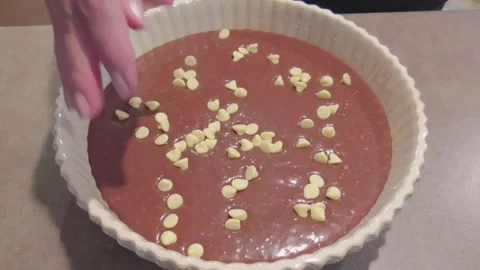 Hand Sprinkling White Chocolate Chips on Cake Batter Stock Footage 345754743