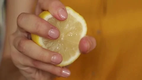 Hand squeeze fresh lemon, juice drains from the pulp and drips. Squeezing out Видео 336588873