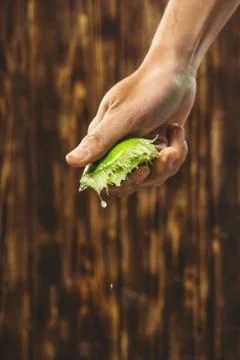 Hand squeeze lime with lime drop on wooden background Stock Photos