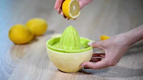 Hand with Squeezer Squeezing Lemon Juice out of lemon. Yellow vibrant color. Stock Footage 265838506