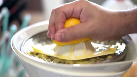 Hand with Squeezer Squeezing Lemon Juice out of lemon. Yellow vibrant color. Stock Footage 265838911