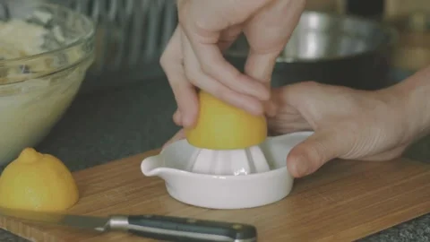 Hand with Squeezer Squeezing Lemon Juice out of lemon. Yellow vibrant color. Stock Footage 265838964