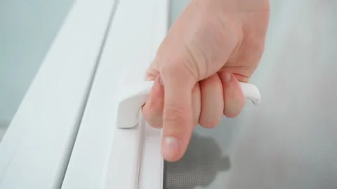A hand squeezes the hand of the white door and slowly and hesitantly releases it Stock Footage 228665469
