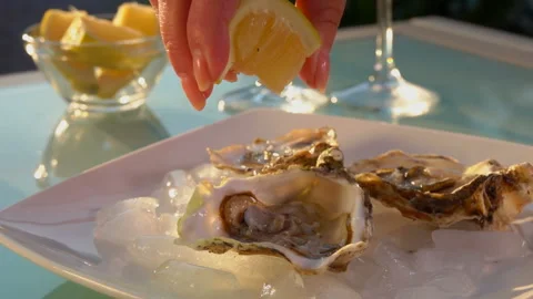 Hand squeezes juice from lemon into open oysters Stock Footage 108565382
