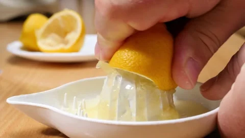Hand squeezes lemon juice on squeezer in close up. Lemon being pressed and juice Video stock 336588794